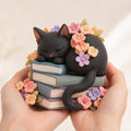 Black Cat Sleeping on Books Figurine, Floral Crown, held in a hand for scale