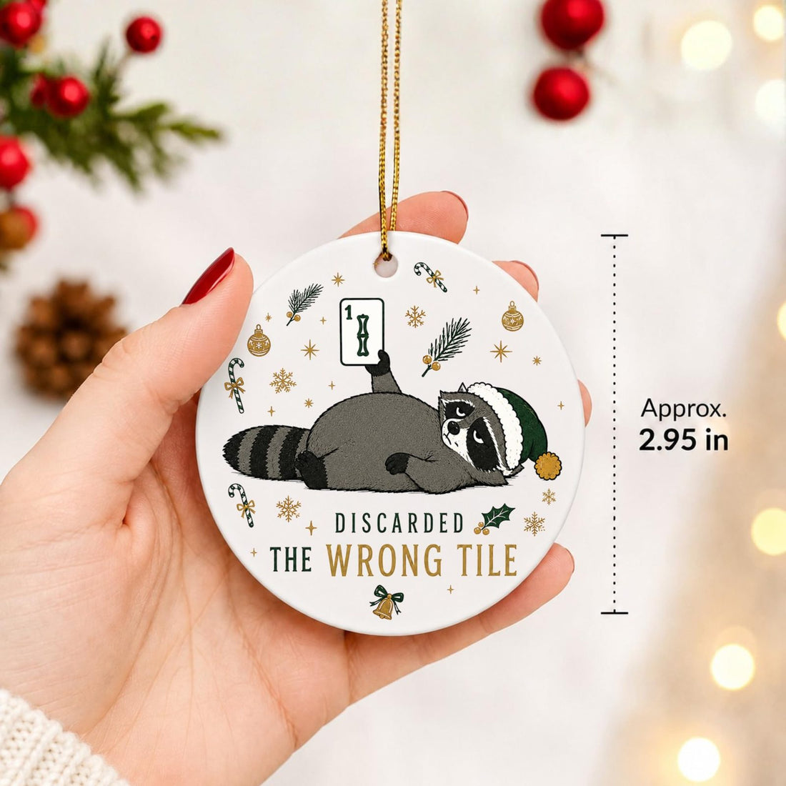 Round acrylic ornament with a tired raccoon in a green Santa hat holding up a mahjong tile and the words Discarded the Wrong Tile